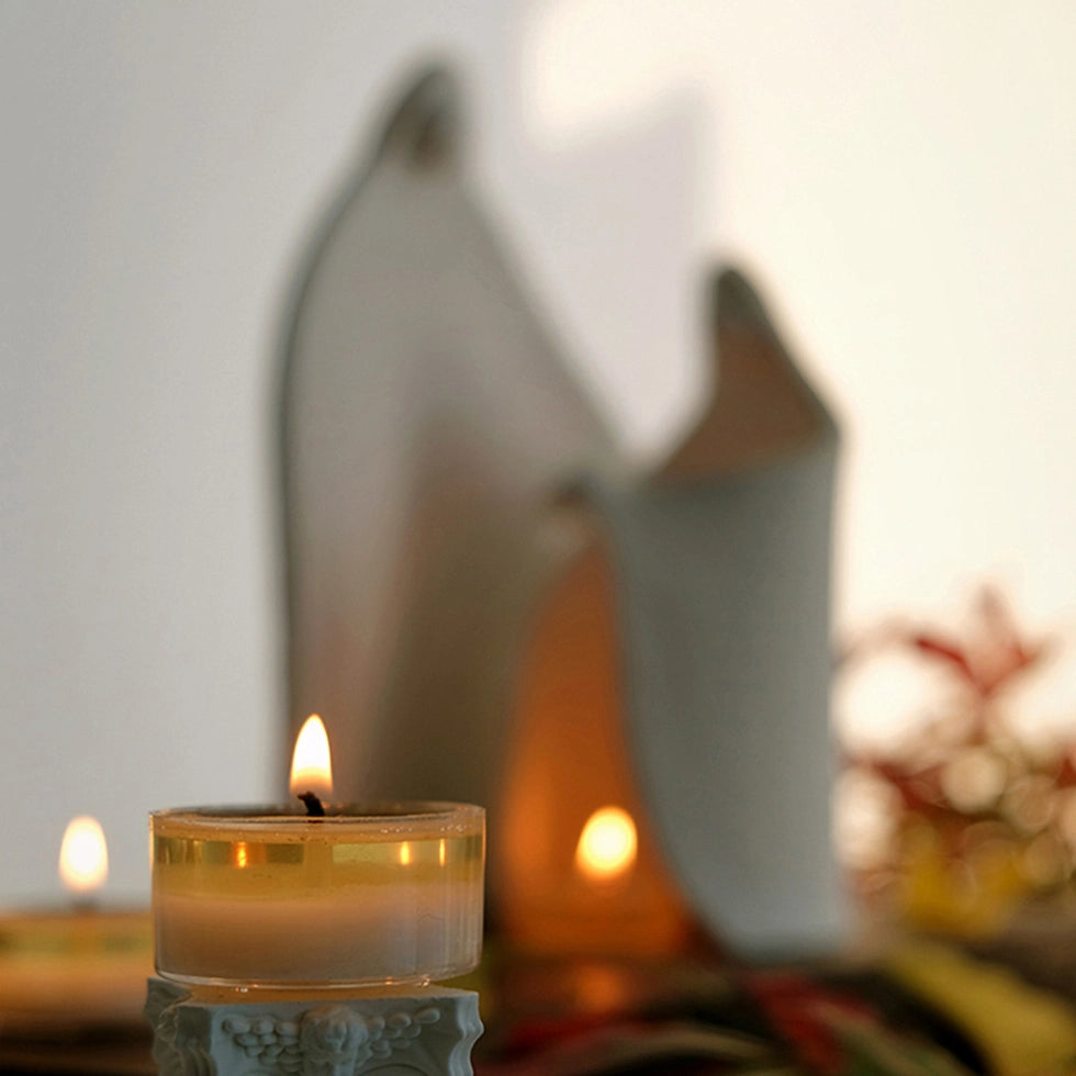 Ceramic family candle holder on a wooden table with burning tealights