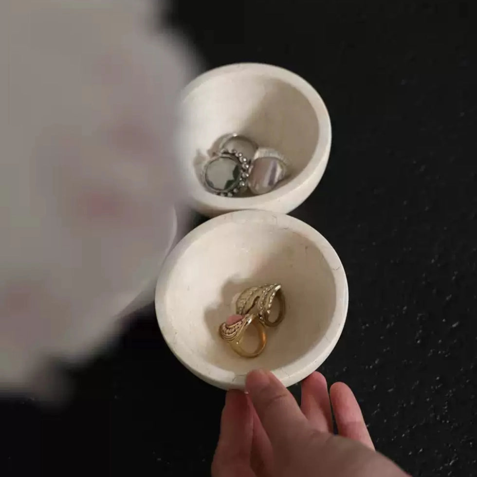 White jewelry box with gold and silver earrings on a black table