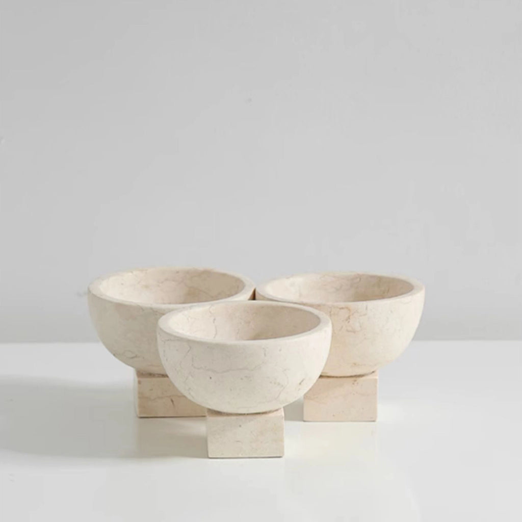 Three stone bowls on a white surface with a light gray background