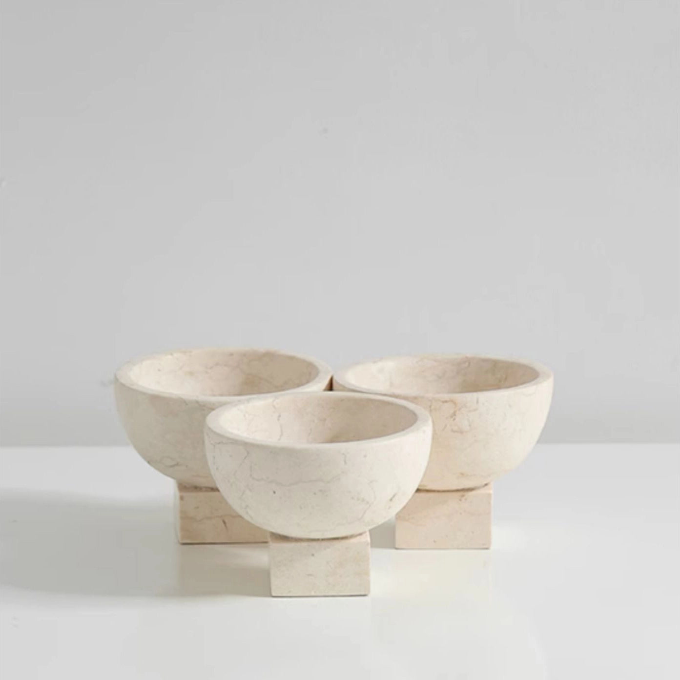 Three stone bowls on a white surface with a light gray background