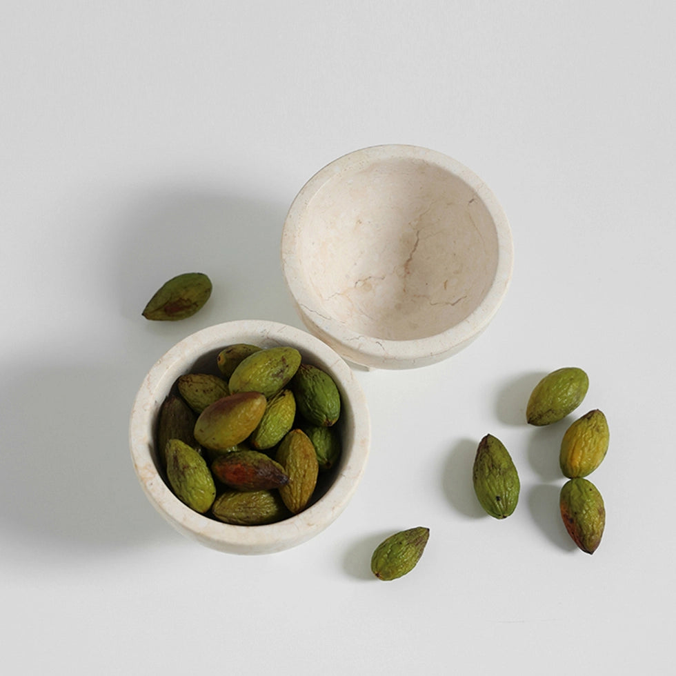 Green olives in a white marble bowl on a light gray background