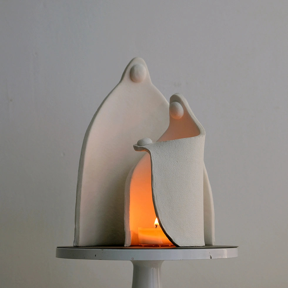 Ceramic sculpture of a family with a candle inside on a gray background