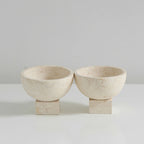 Two beige stone bowls on a light gray background