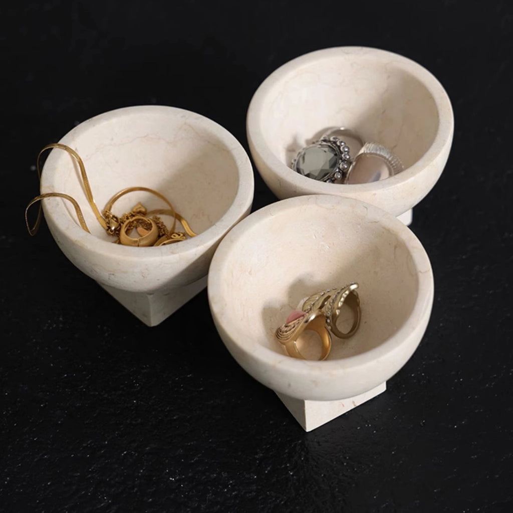Natural stone marble dish displaying necklaces and bracelets on a bedside table