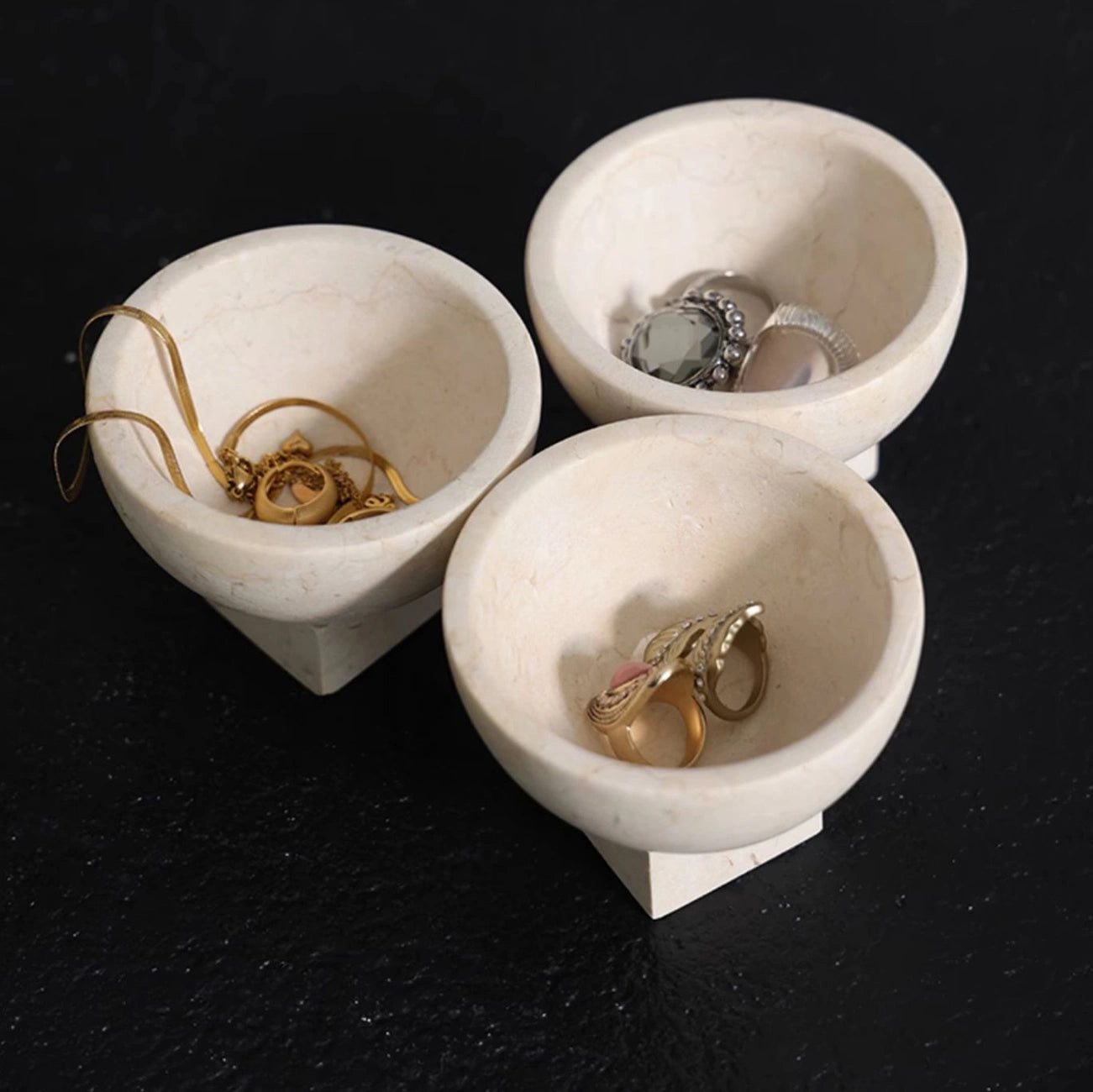 Natural stone marble dish displaying necklaces and bracelets on a bedside table
