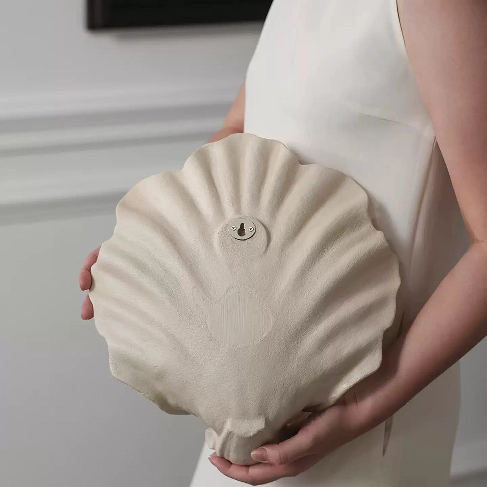 Person holding a large shell-shaped candle holder